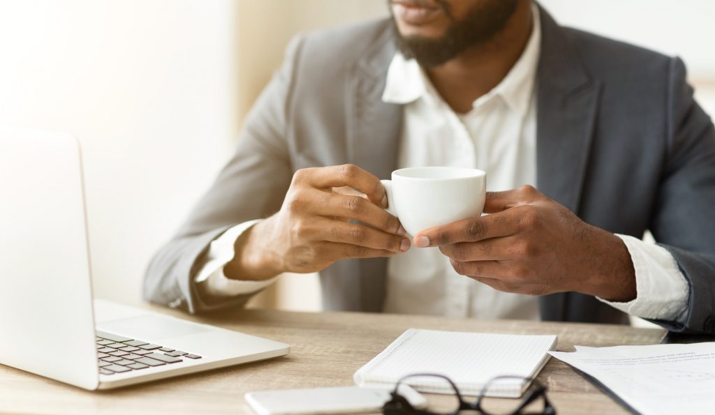 Pensive businessman drinking coffee at workplace, thinking about new project